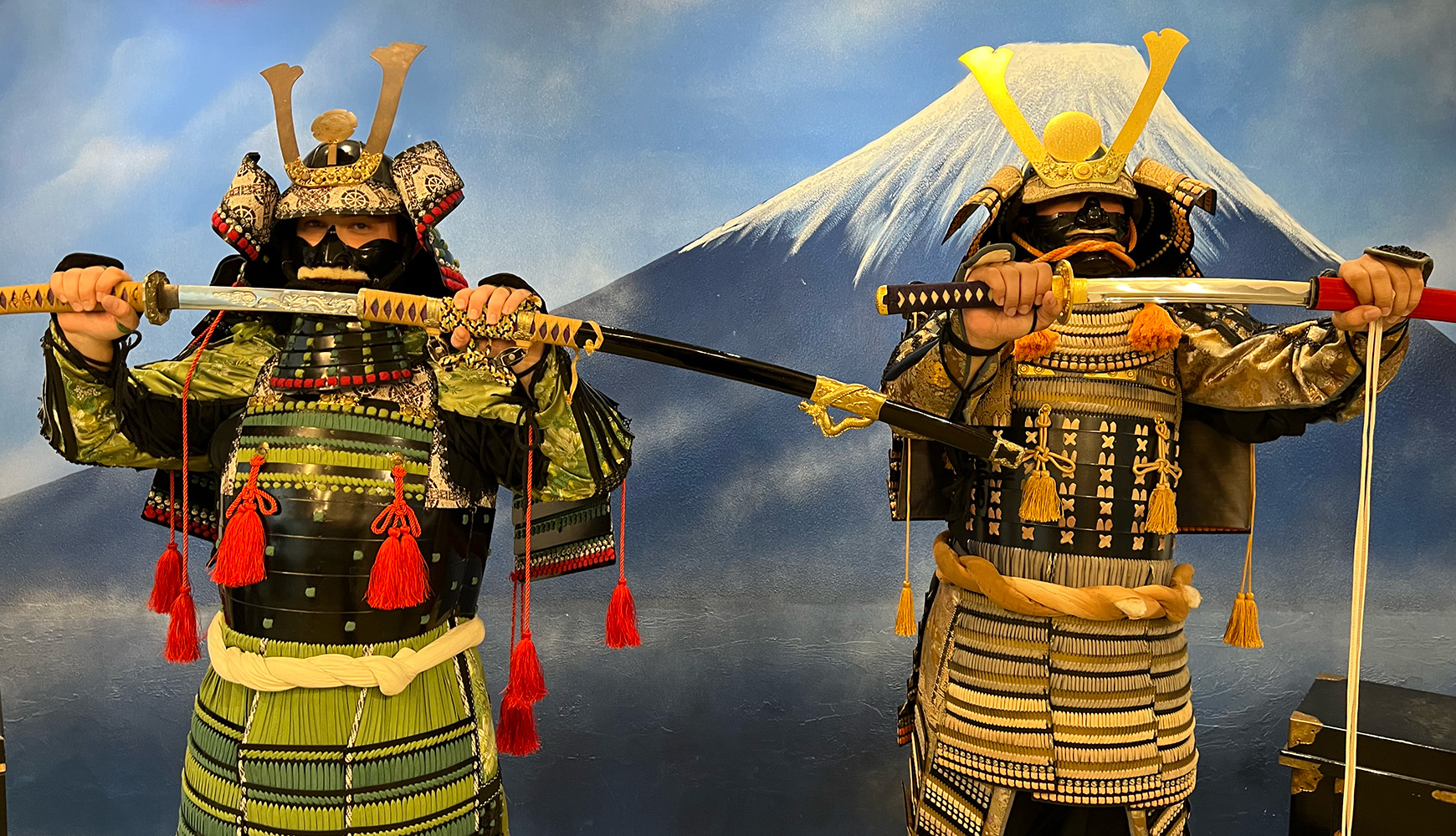Two visitors posing in full samurai armor with katana at Yushinkan Kyoto