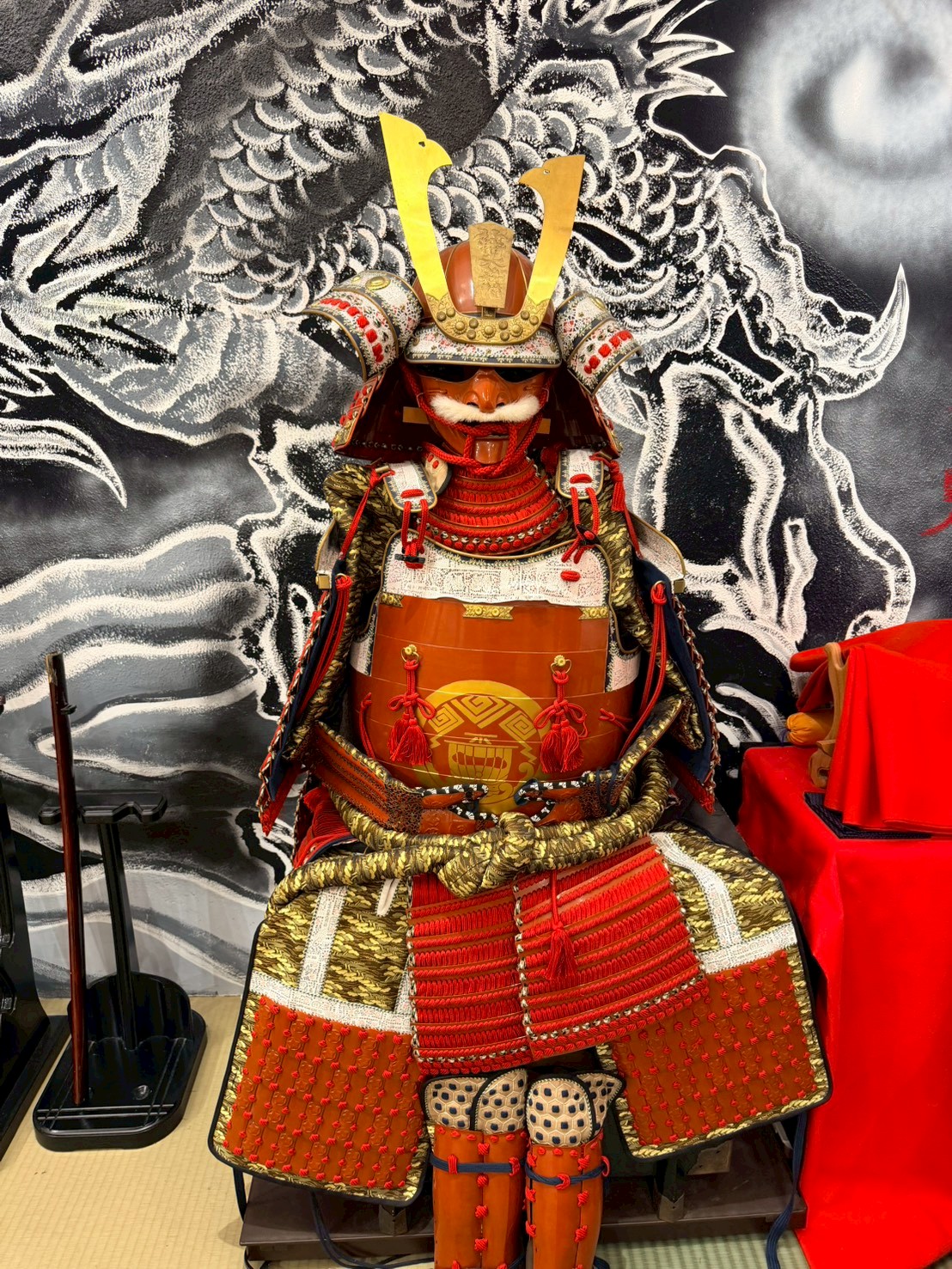 Full red-laced samurai armor with golden crest at Yushinkan Kyoto