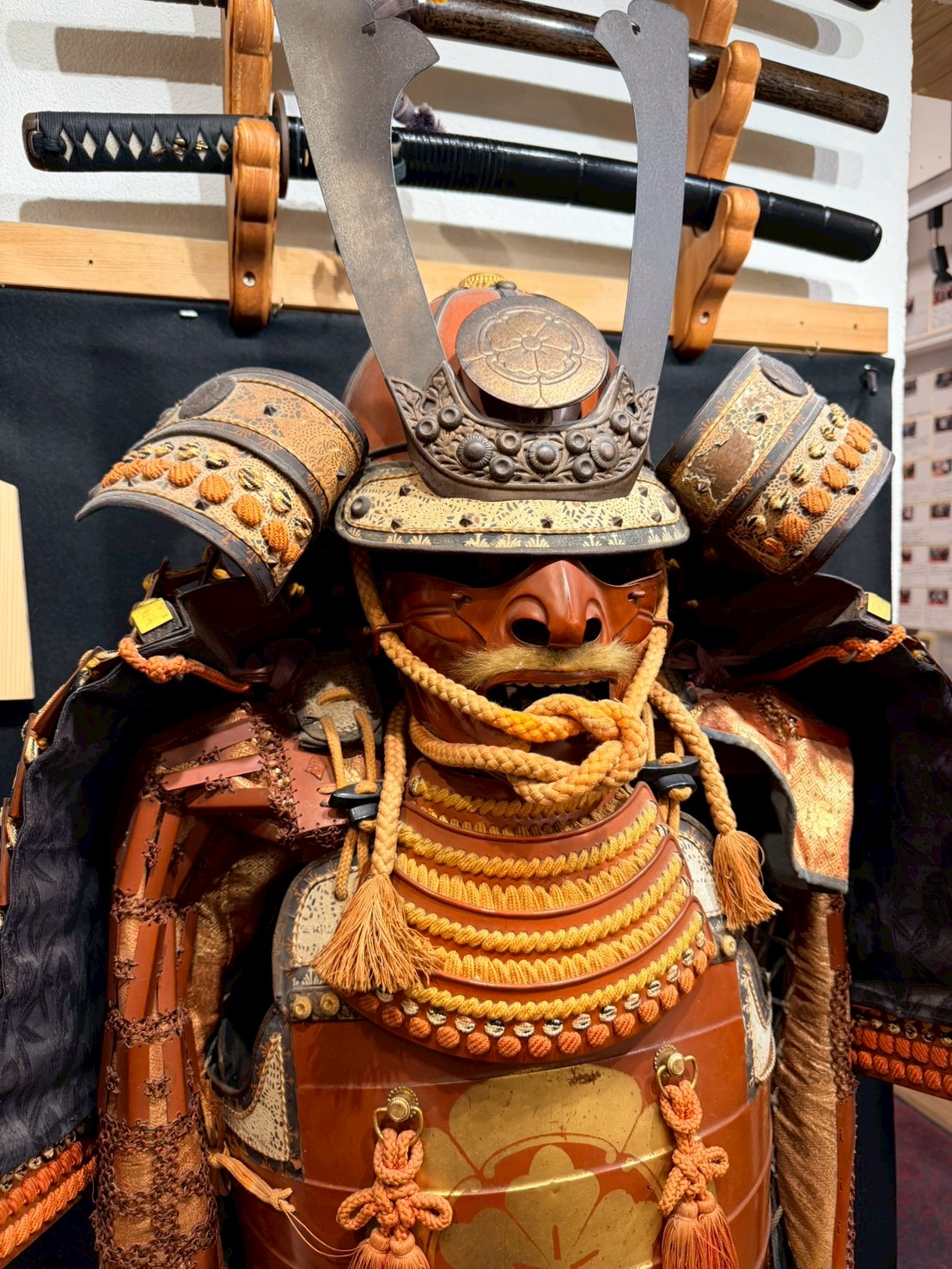 Samurai armor (gusoku) with helmet displayed below mounted swords